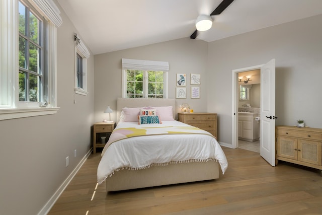 bedroom featuring hardwood / wood-style flooring, ceiling fan, ensuite bathroom, and vaulted ceiling