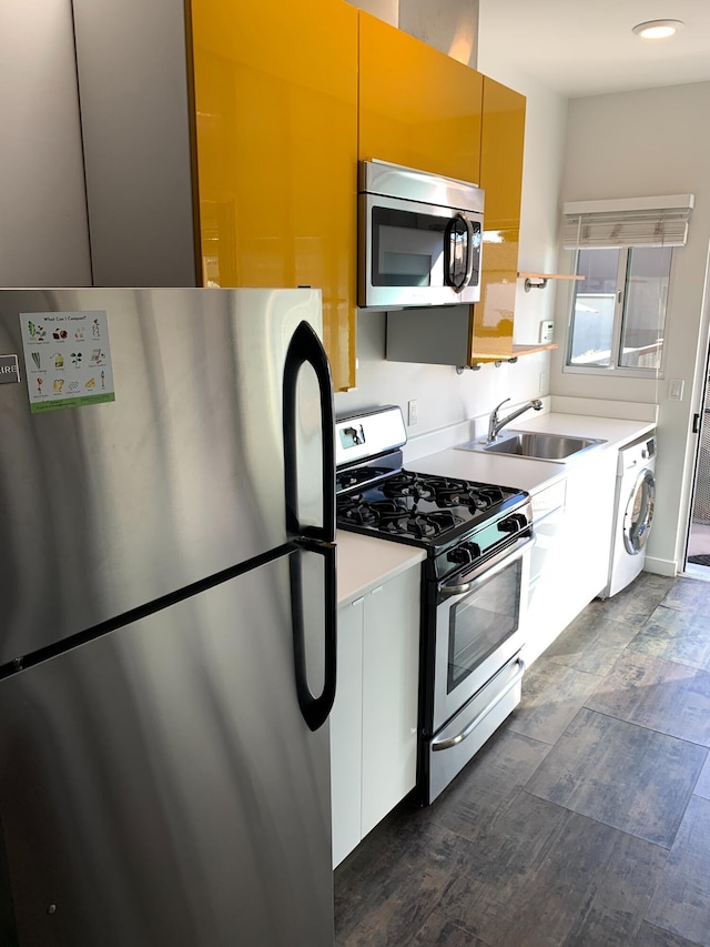 kitchen with washer / dryer, white cabinetry, sink, and appliances with stainless steel finishes