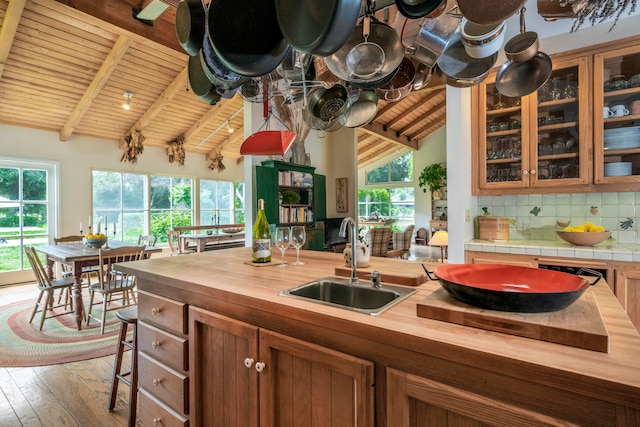 kitchen featuring wood counters, wooden ceiling, decorative backsplash, lofted ceiling with beams, and sink