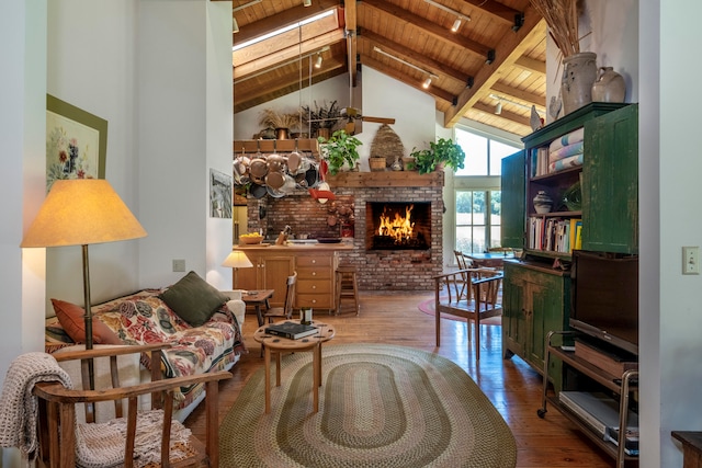 sitting room with a fireplace, wooden ceiling, hardwood / wood-style floors, high vaulted ceiling, and beam ceiling