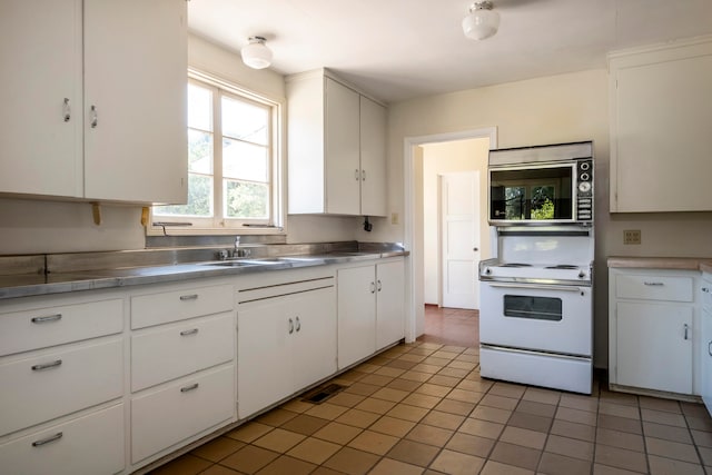 kitchen with stainless steel counters, white cabinetry, light tile patterned floors, and white electric range oven