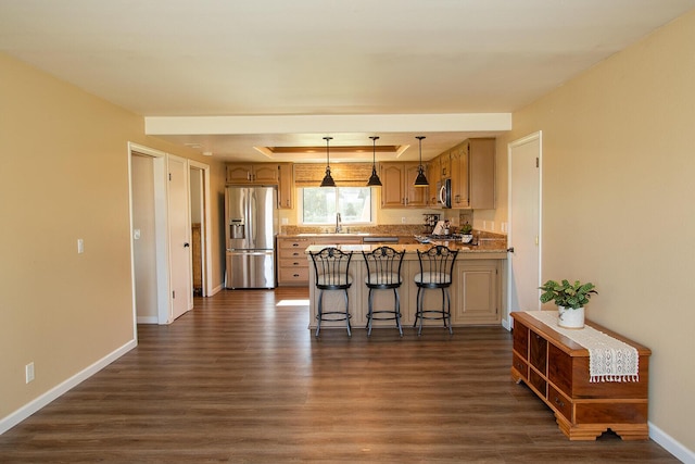 kitchen with kitchen peninsula, appliances with stainless steel finishes, a kitchen breakfast bar, sink, and dark hardwood / wood-style floors