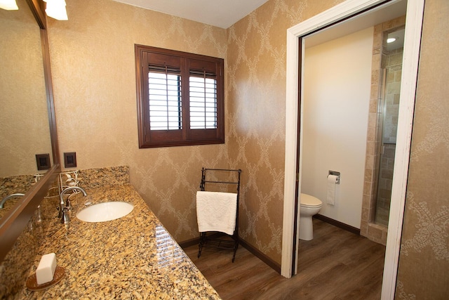 bathroom with hardwood / wood-style floors, vanity, toilet, and a shower