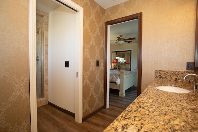 bathroom with wood-type flooring, vanity, a shower with door, and ceiling fan