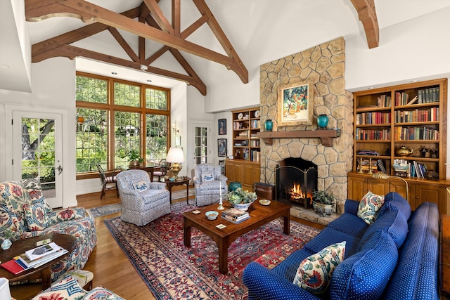 living room featuring built in features, a stone fireplace, beam ceiling, high vaulted ceiling, and wood-type flooring