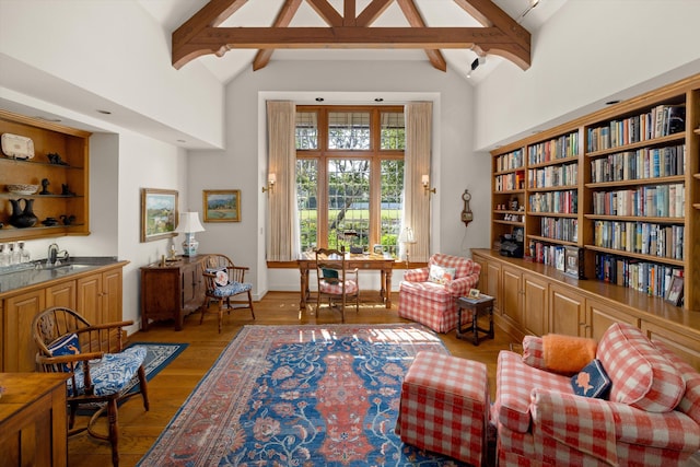 living area featuring beam ceiling, built in shelves, hardwood / wood-style floors, and high vaulted ceiling