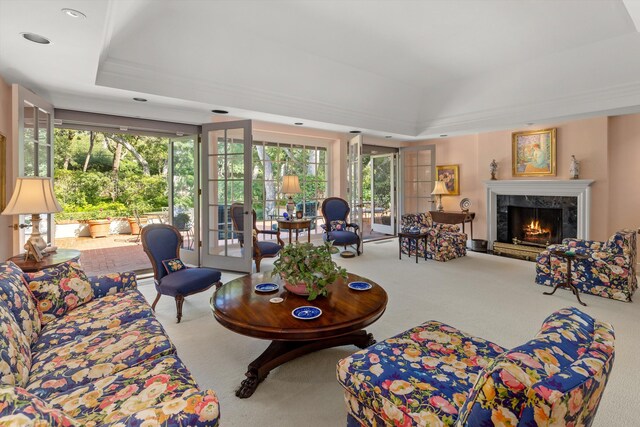 living room with carpet floors, a high end fireplace, and a raised ceiling