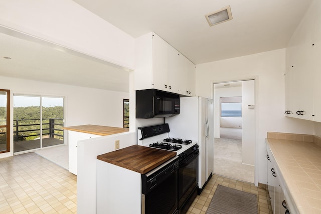 kitchen featuring white cabinetry, tile counters, light colored carpet, and black appliances