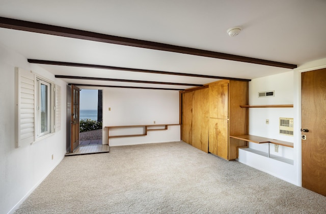 unfurnished living room with carpet flooring, beam ceiling, and heating unit