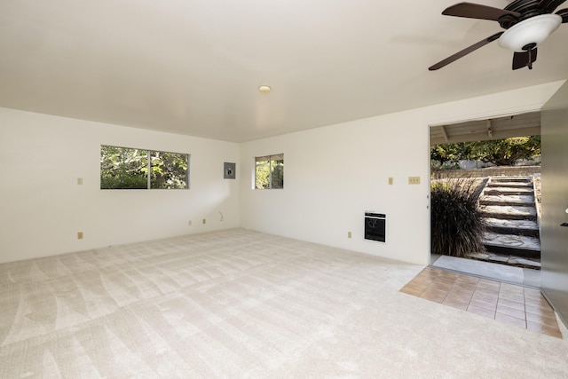 interior space featuring ceiling fan, electric panel, light carpet, and heating unit