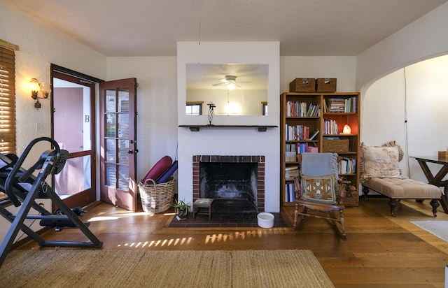 interior space with arched walkways, a fireplace, and wood finished floors