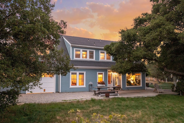 back house at dusk featuring a patio area and a yard