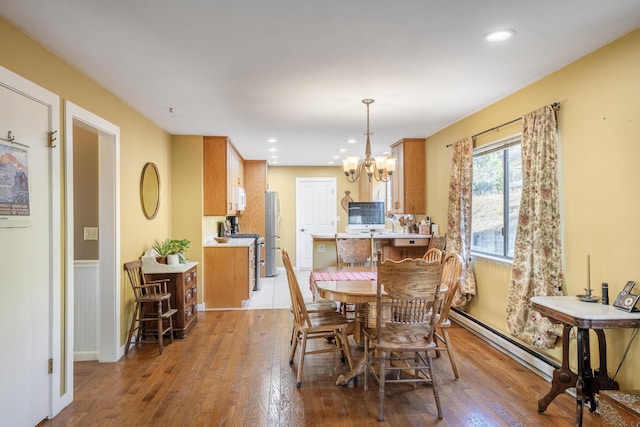 dining space featuring light hardwood / wood-style floors, a chandelier, and baseboard heating