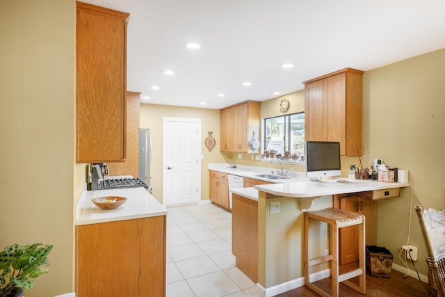 kitchen with kitchen peninsula, a kitchen breakfast bar, white dishwasher, sink, and range