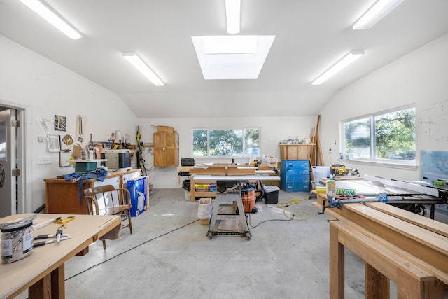 misc room featuring concrete floors, vaulted ceiling with skylight, and a workshop area