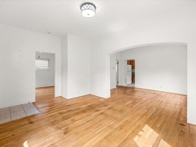 empty room featuring light wood-type flooring and arched walkways