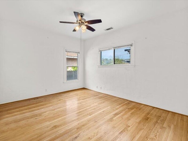 spare room with a ceiling fan, visible vents, and wood finished floors