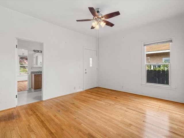 unfurnished room featuring a ceiling fan, plenty of natural light, and light wood-style flooring