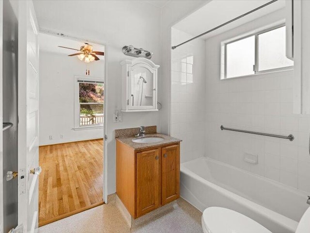 full bath with shower / bathtub combination, toilet, a ceiling fan, vanity, and wood finished floors