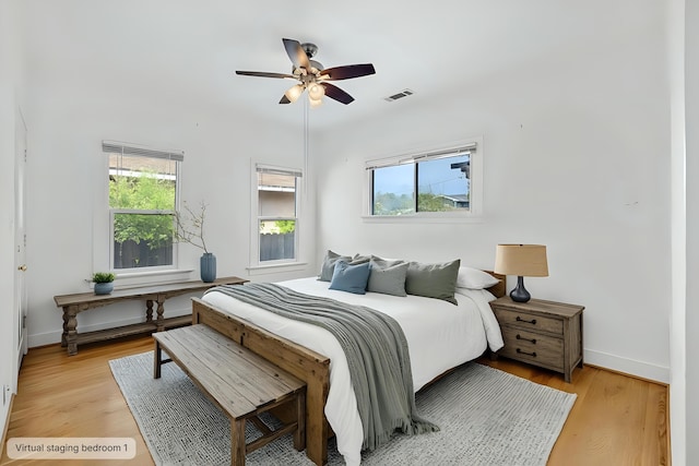 bedroom with light wood-type flooring, baseboards, visible vents, and a ceiling fan