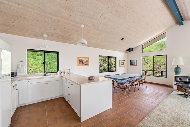 kitchen with white cabinets, dark tile patterned floors, sink, hanging light fixtures, and kitchen peninsula