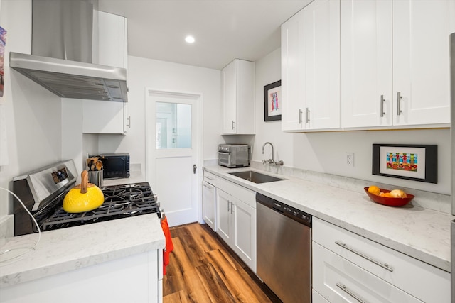 kitchen with appliances with stainless steel finishes, white cabinets, sink, and wall chimney exhaust hood