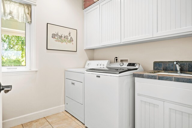 washroom featuring sink, cabinets, washing machine and dryer, and light tile patterned floors