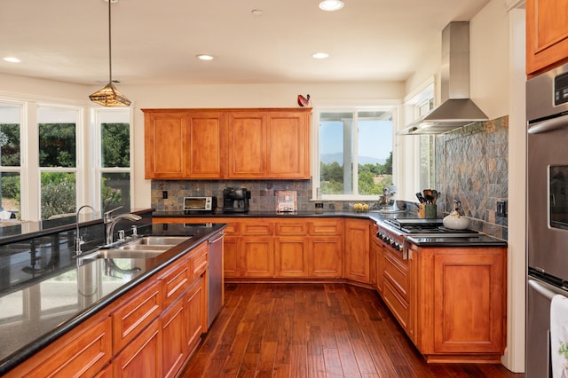 kitchen featuring wall chimney range hood, dark wood-type flooring, decorative backsplash, decorative light fixtures, and sink