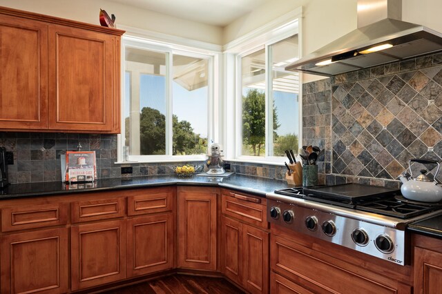 kitchen with cooktop, tasteful backsplash, dark hardwood / wood-style flooring, dark stone countertops, and range hood