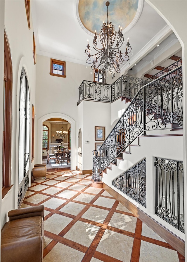 foyer featuring ornamental molding, a towering ceiling, and a notable chandelier