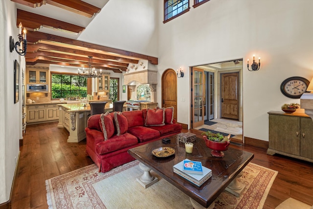 living room with beamed ceiling, a towering ceiling, a chandelier, and light hardwood / wood-style flooring