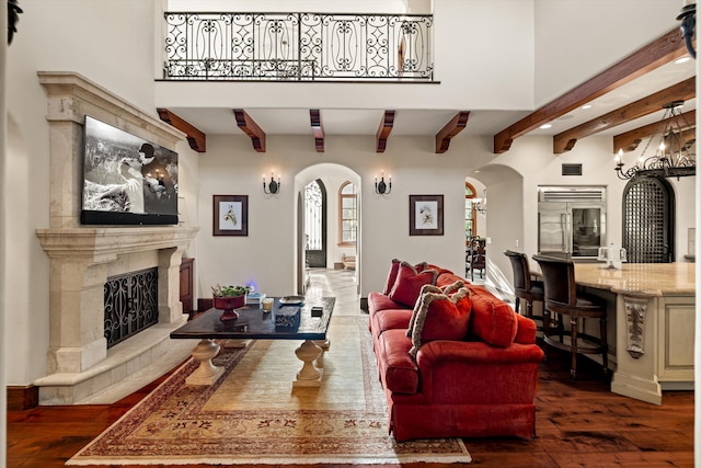 living room with beamed ceiling, dark hardwood / wood-style flooring, a towering ceiling, and a fireplace