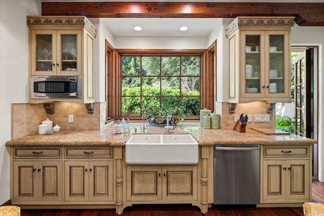 kitchen featuring sink, appliances with stainless steel finishes, cream cabinetry, light stone countertops, and backsplash