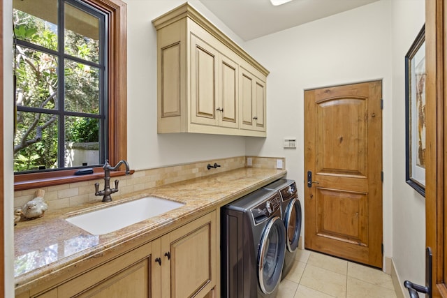 clothes washing area featuring cabinets, sink, light tile patterned floors, and washing machine and clothes dryer