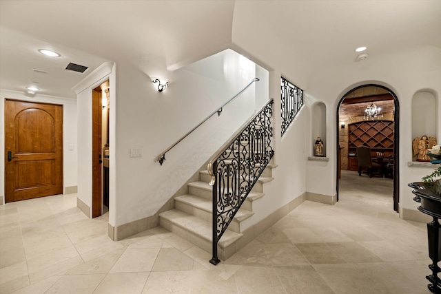 stairway with tile patterned flooring and a notable chandelier