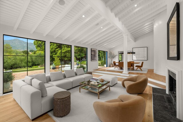 living room featuring a towering ceiling, light wood-type flooring, wood ceiling, beam ceiling, and a mountain view