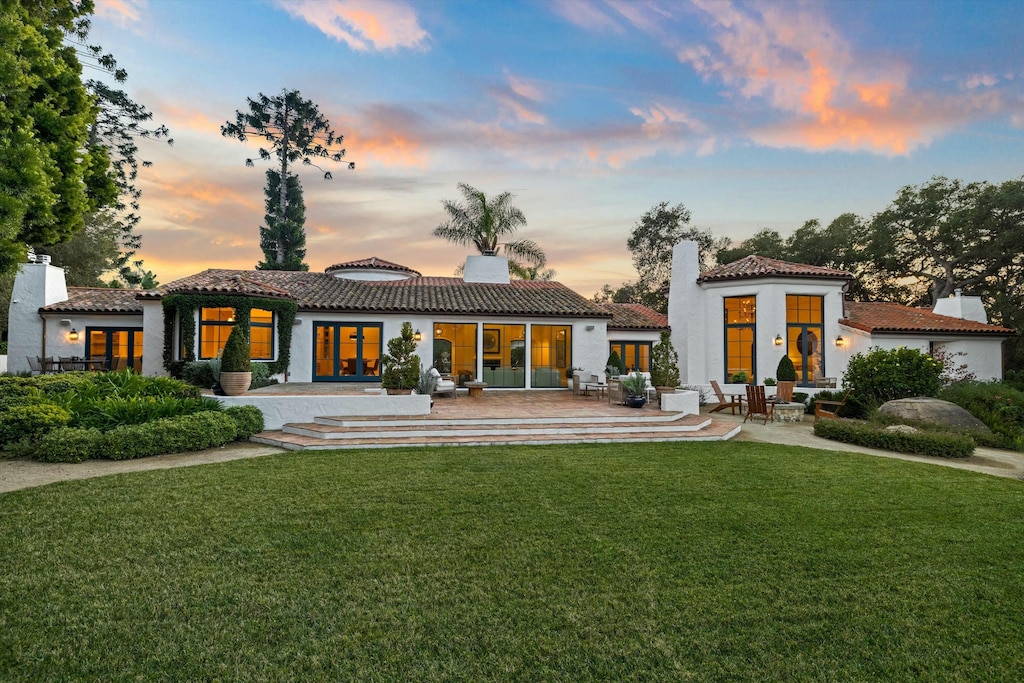 back house at dusk with a yard and a patio