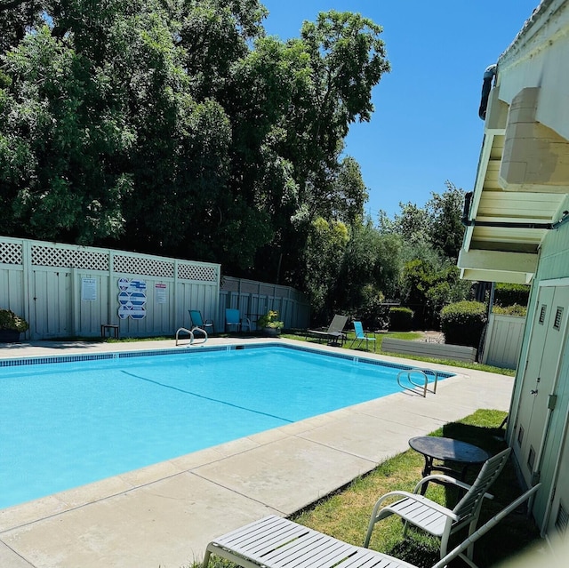 pool with a patio area and fence