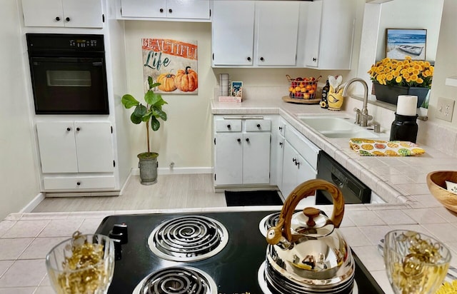 kitchen featuring tile counters, white cabinetry, a sink, black appliances, and baseboards