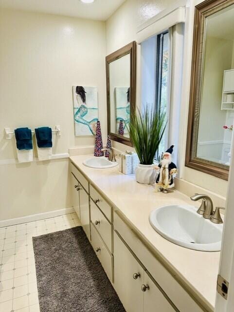 bathroom featuring double vanity, baseboards, a sink, and tile patterned floors