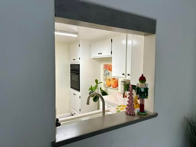 kitchen featuring white cabinets, a sink, and black oven