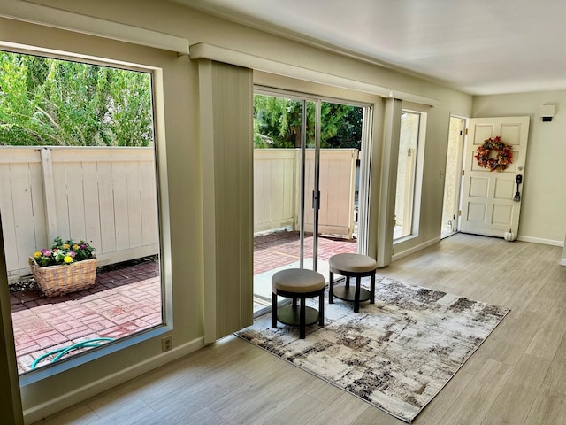 doorway to outside with light wood-style flooring and baseboards