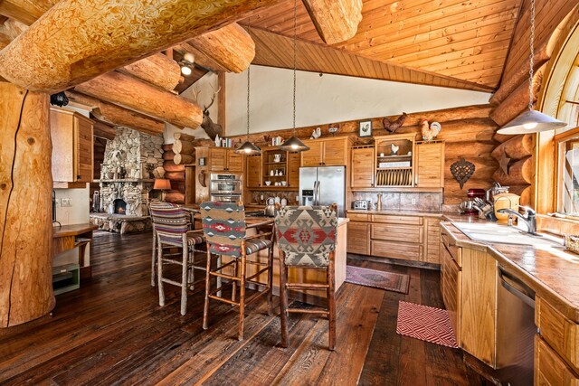 kitchen with appliances with stainless steel finishes, dark wood-type flooring, high vaulted ceiling, decorative light fixtures, and rustic walls