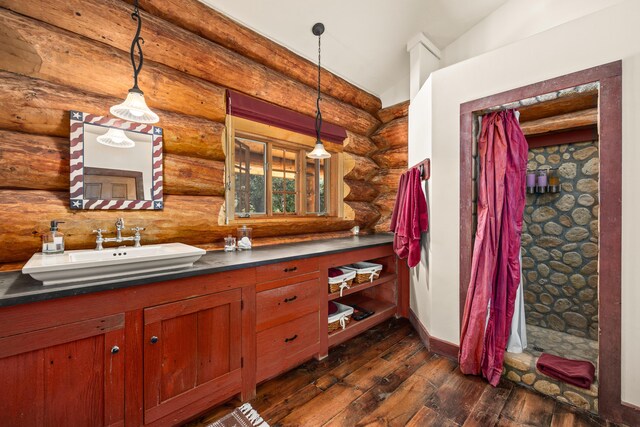 bathroom with lofted ceiling, wood-type flooring, log walls, and vanity