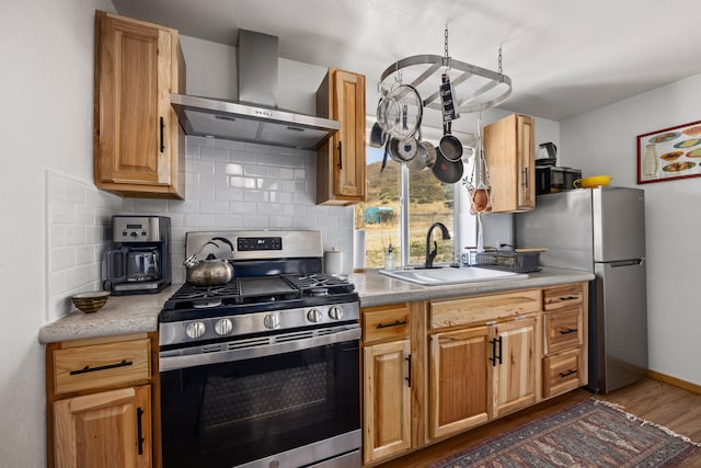 kitchen with decorative backsplash, dark hardwood / wood-style floors, appliances with stainless steel finishes, wall chimney range hood, and sink