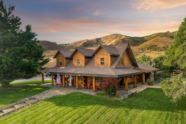 view of front of property featuring a lawn, stairs, a patio, and a mountain view
