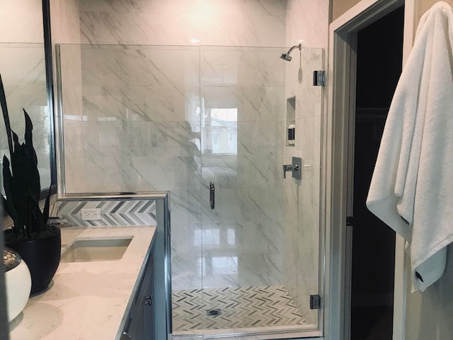 bathroom with a shower with shower door and vanity