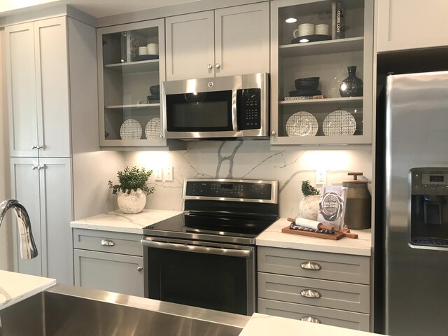 kitchen featuring gray cabinets, sink, stainless steel appliances, and decorative backsplash