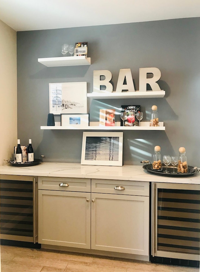 bar with beverage cooler and light wood-type flooring