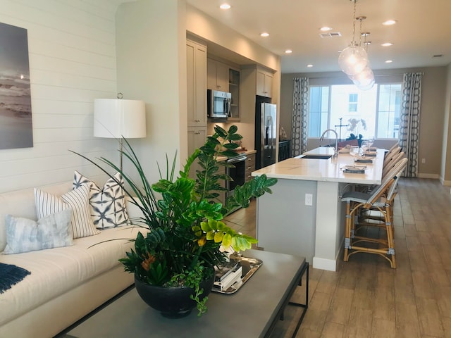 living room featuring hardwood / wood-style floors, sink, and wooden walls